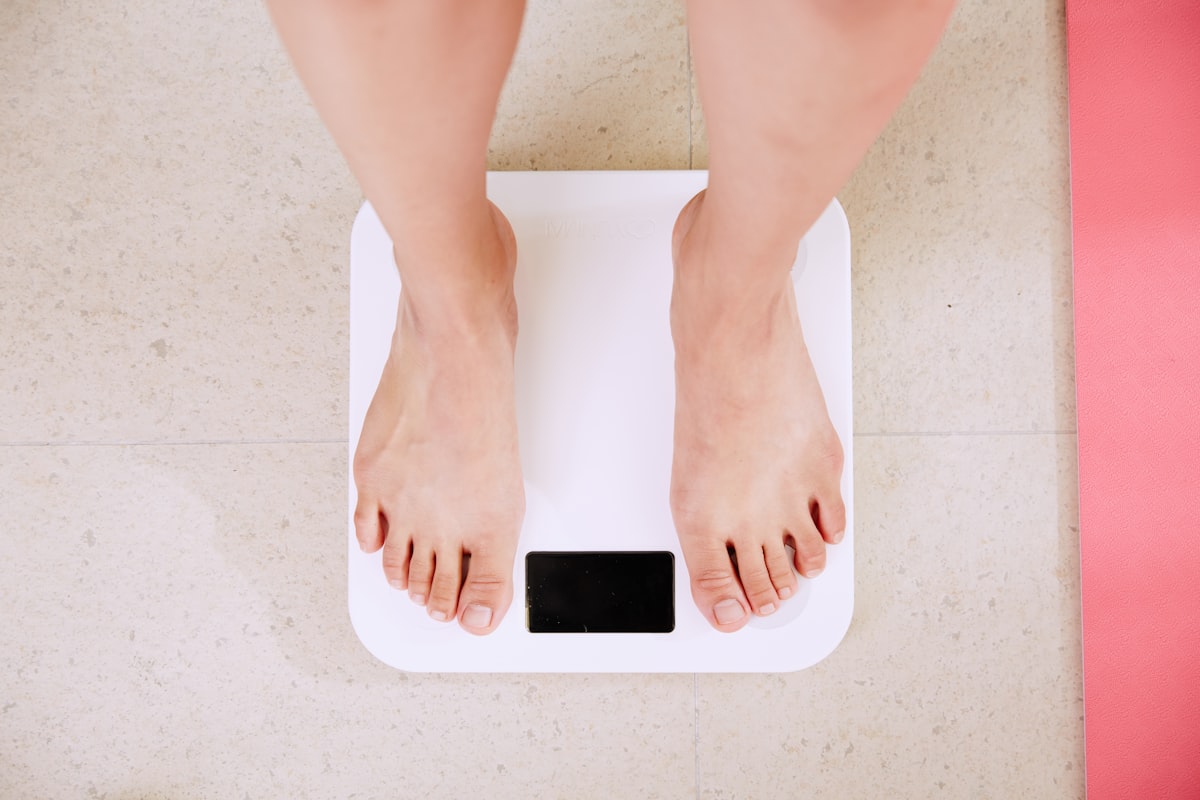 Persoană pe cântar digital, simbol pentru evaluarea indicelui de masă corporală